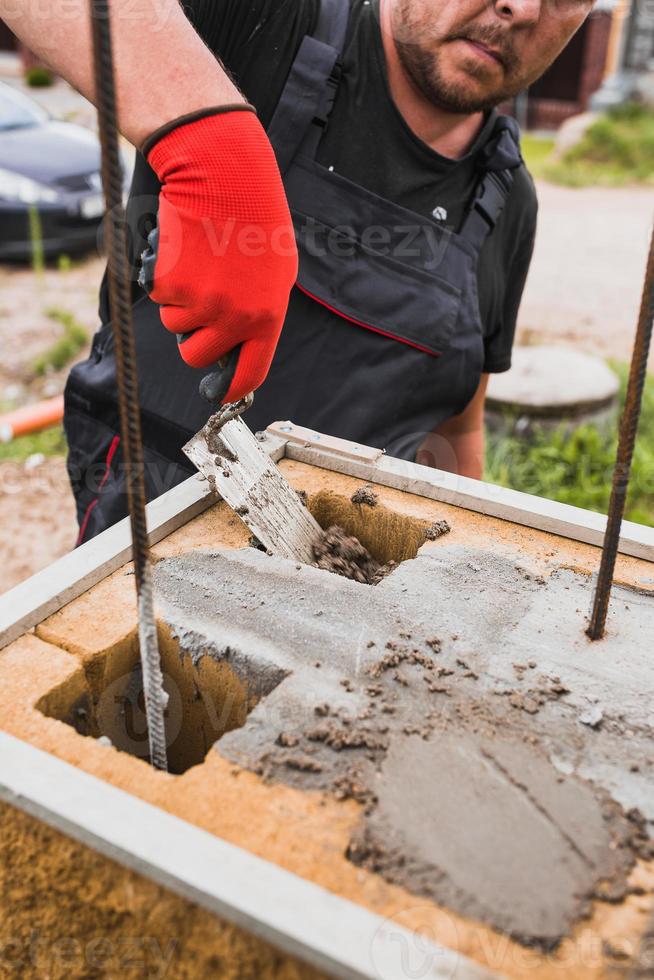 handen van een professionele metselaar tijdens het werken op een bouwplaats - gemetselde muur van een betonblok foto