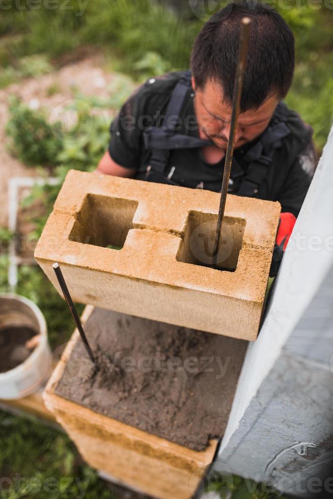 handen van een professionele metselaar tijdens het werken op een bouwplaats - gemetselde muur van een betonblok foto