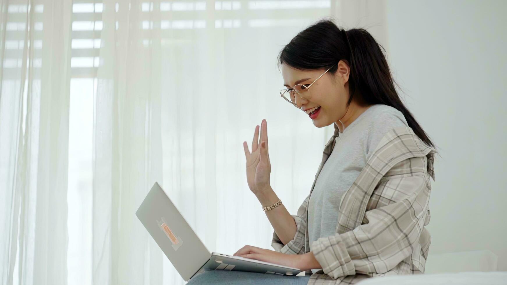 Aziatisch freelance bedrijf vrouw gebruik makend van laptop video telefoontje vriend in bed Bij huis. foto