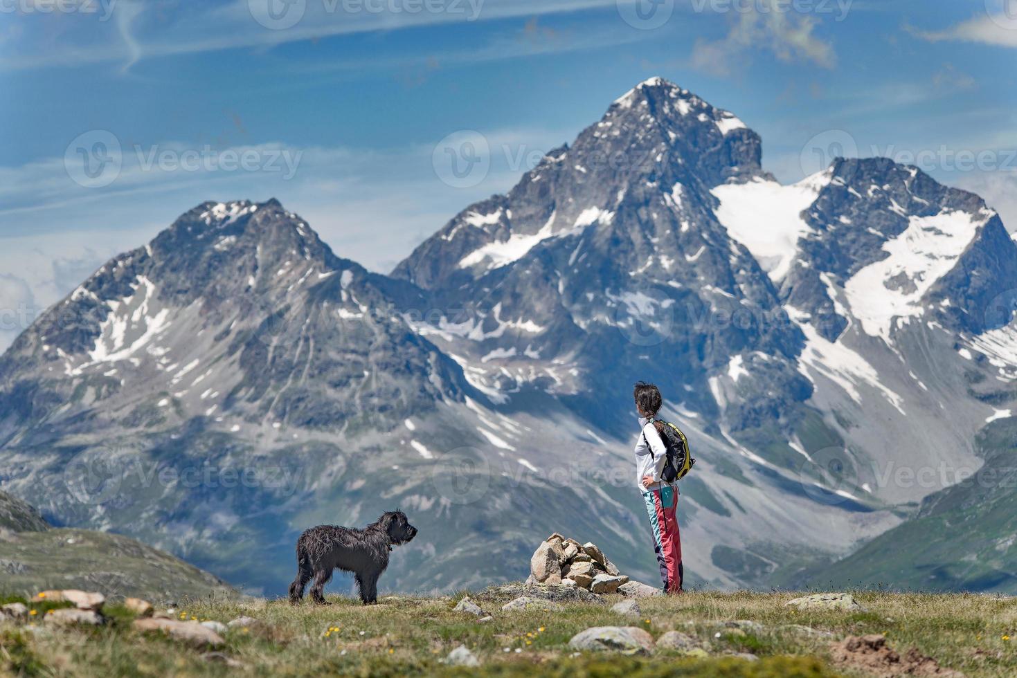 een meisje met haar grote zwarte hond in de bergen geniet van het uitzicht foto