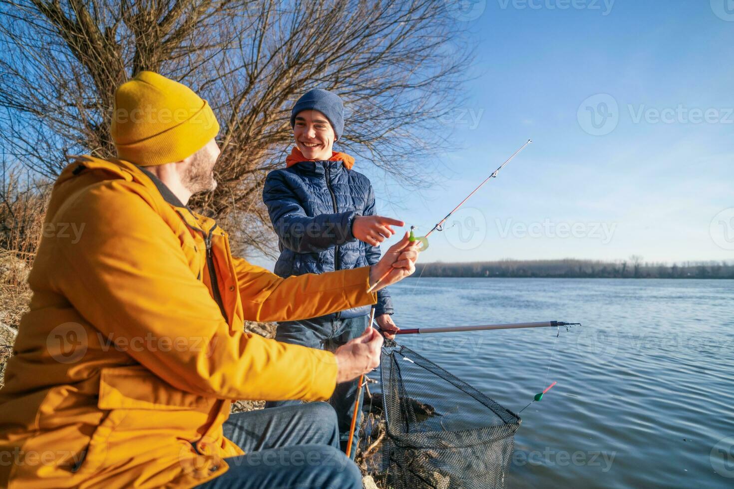 vader en zoon zijn visvangst Aan zonnig winter dag. zoetwater vissen. tiener- jongen is aan het leren naar vis. foto