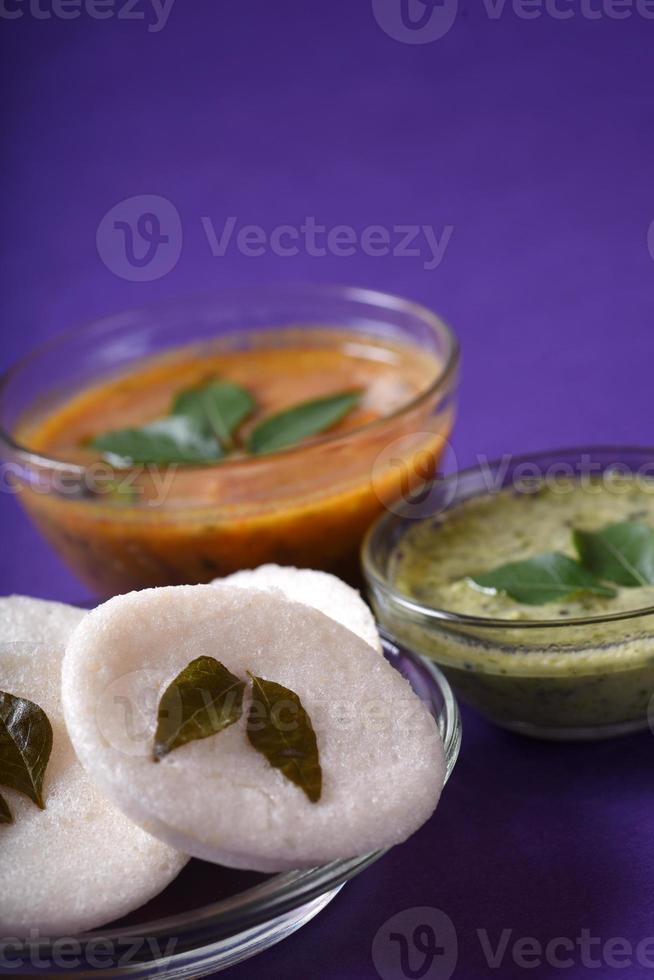 idli met sambar en kokoschutney op violette achtergrond, Indiase schotel Zuid-Indiase favoriete eten rava idli of griesmeel werkeloos of rava nutteloos, geserveerd met sambar en groene chutney. foto