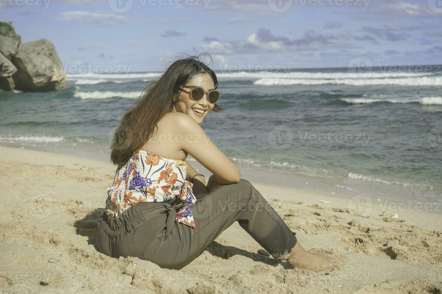 jong Aziatisch vrouw zitten Aan de strand zand. portret sexy Aziatisch dame op reis en ontspannende in de zomer met tropisch natuur. foto