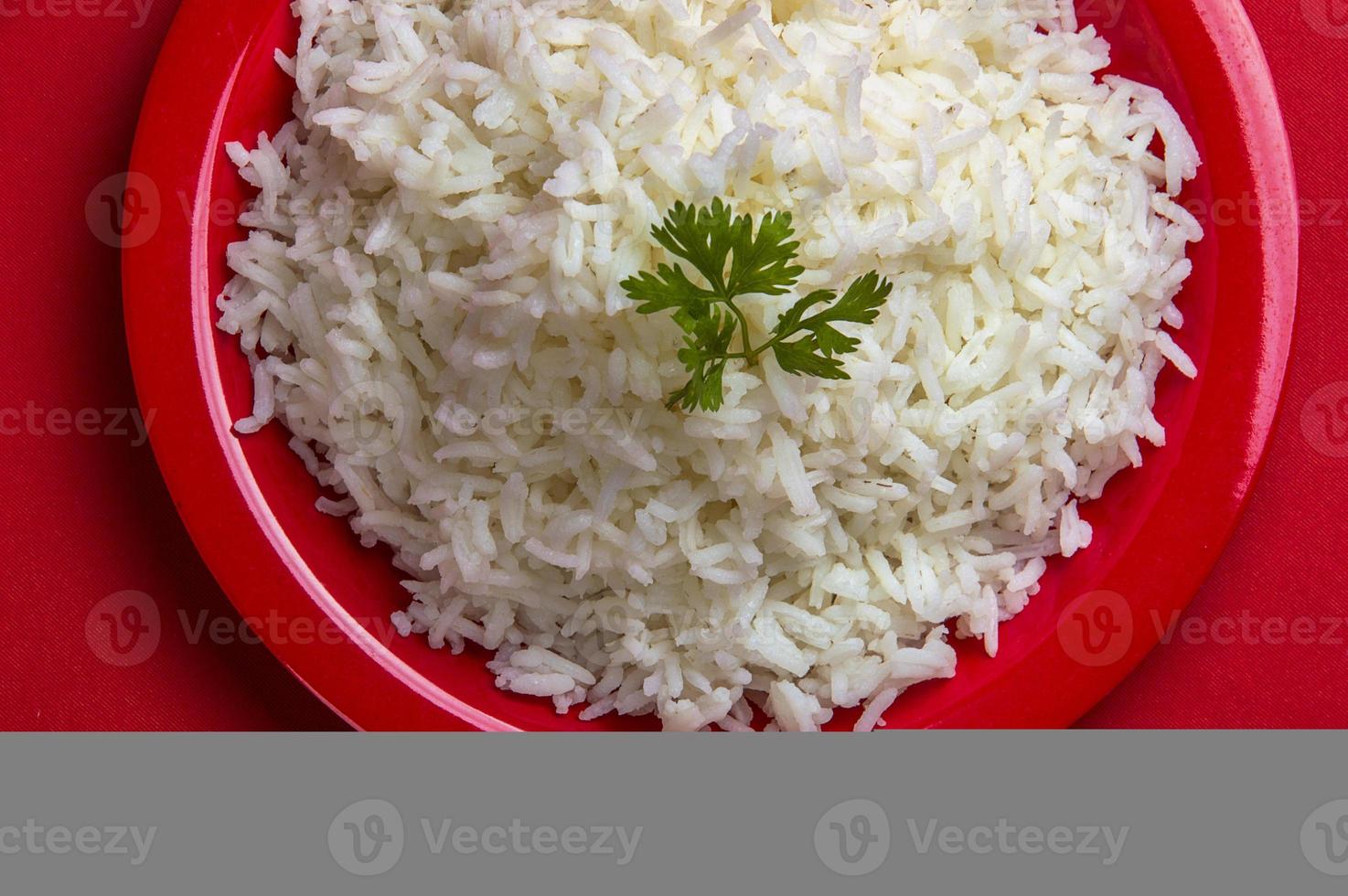 gekookte gewone witte basmatirijst in een rode plaat op rode achtergrond foto
