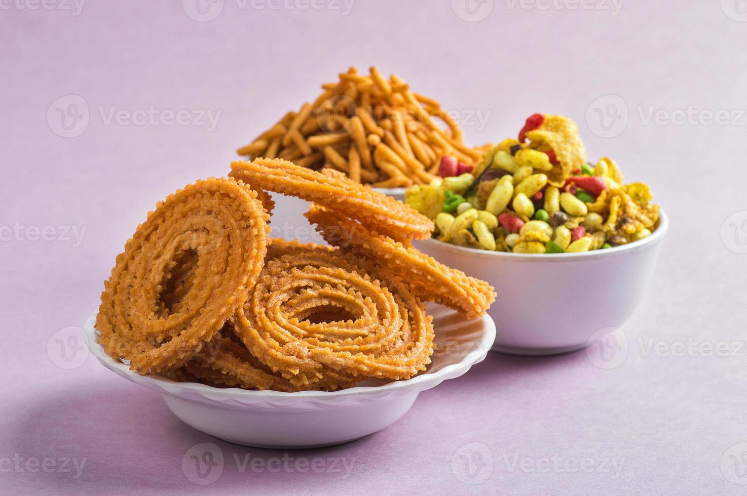 Indiase snack chakli, chakali of murukku en besan gram meel sev en chivada of chiwada op roze achtergrond. diwali eten foto