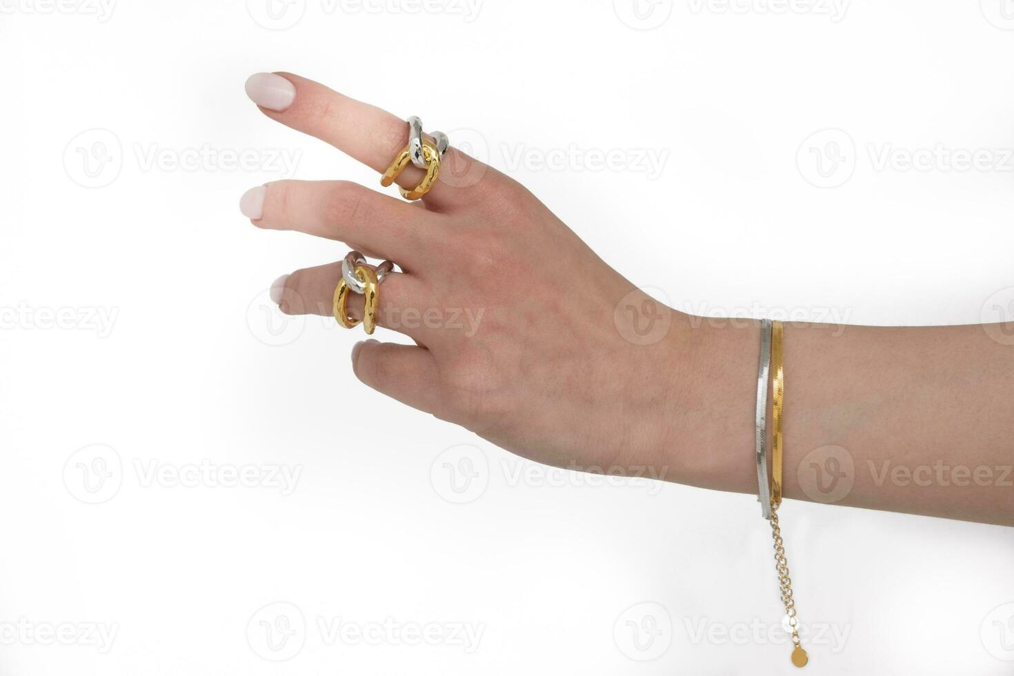 vrouw hand- vervelend slang keten armbanden en met elkaar verbonden gouden en zilver ringen reeks tegen een wit achtergrond. mooi Valentijnsdag geschenk. foto