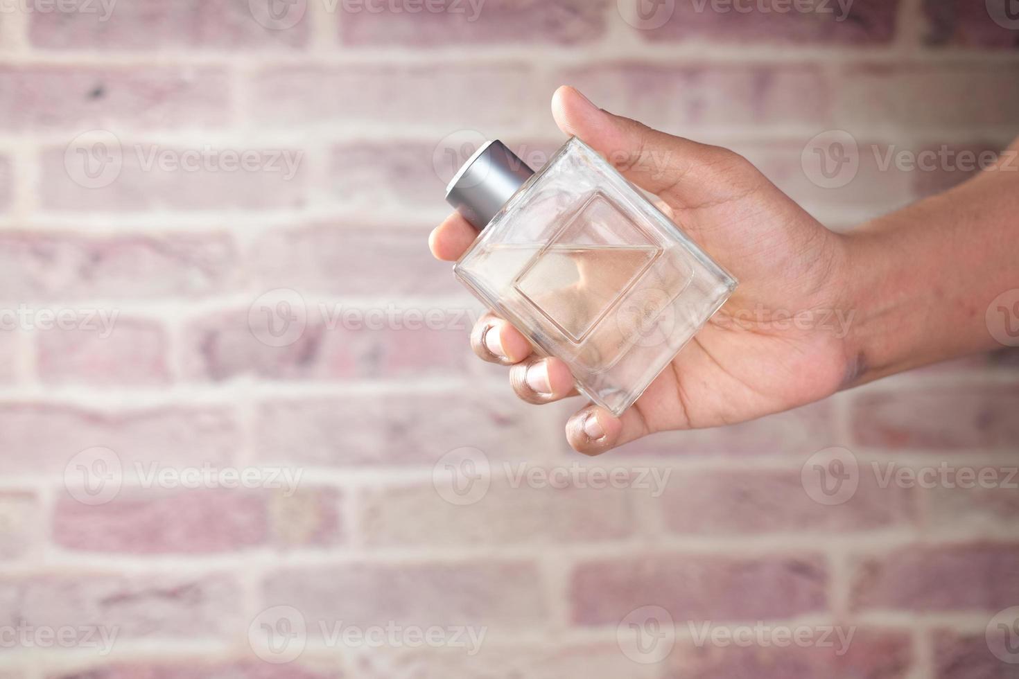 hand houden parfum tegen bakstenen achtergrond foto