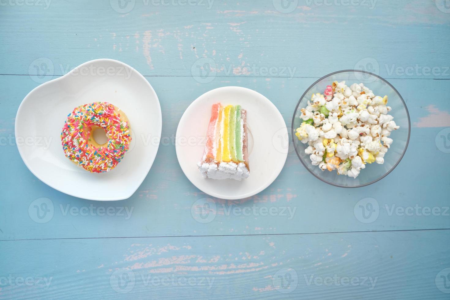 plakje slagroomtaart, donuts en popcorn op tafel foto