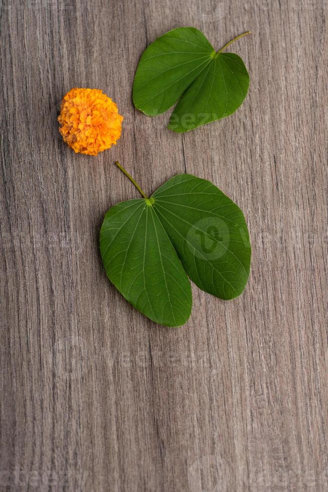 indiase festival dussehra, met gouden blad bauhinia racemosa en goudsbloem bloemen op een houten achtergrond. foto