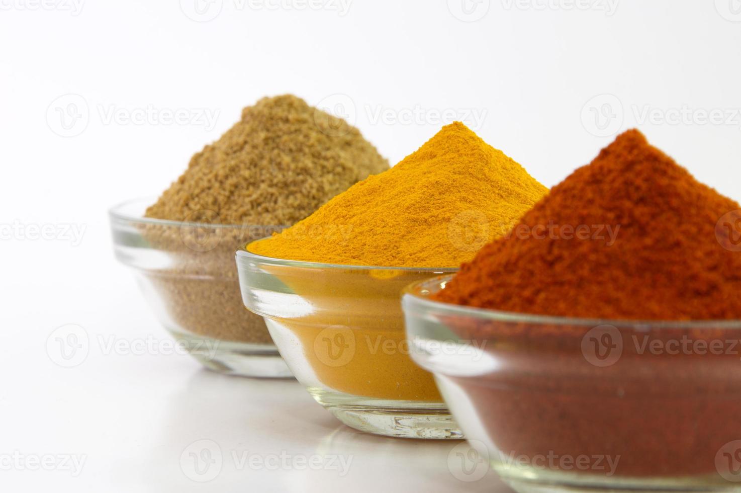 Spice poeder chili, kurkuma en koriander in kom geïsoleerd op een witte achtergrond. foto