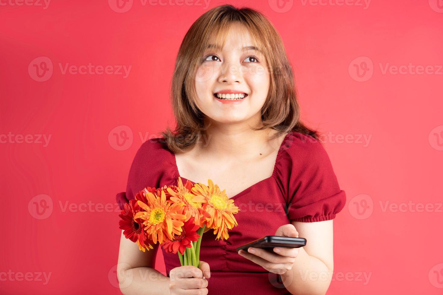 jong meisje dat bloemen vasthoudt en telefoon gebruikt met een vrolijke uitdrukking op de achtergrond foto