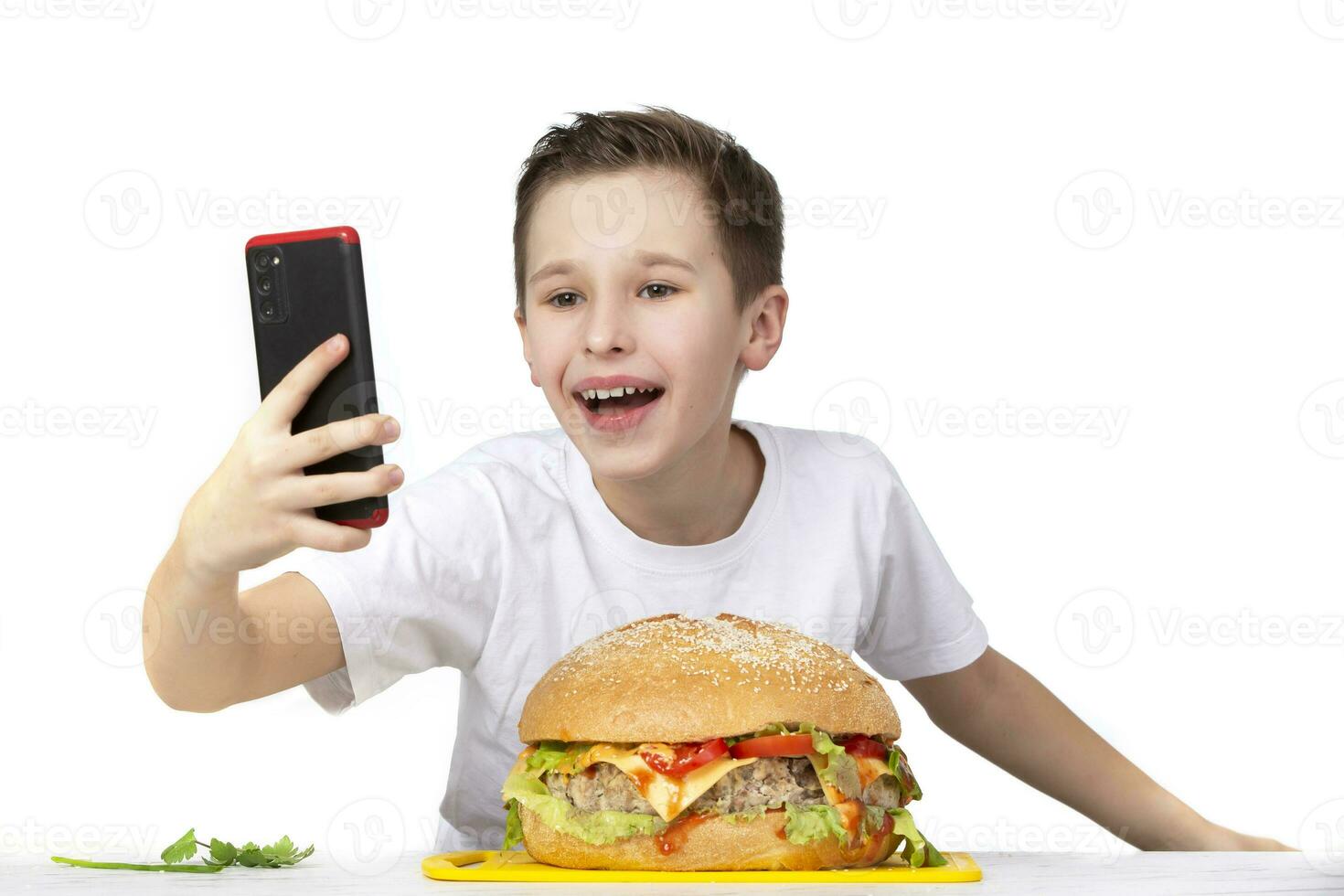een jong jongen duurt een selfie met een groot Hamburger, geïsoleerd in wit. foto