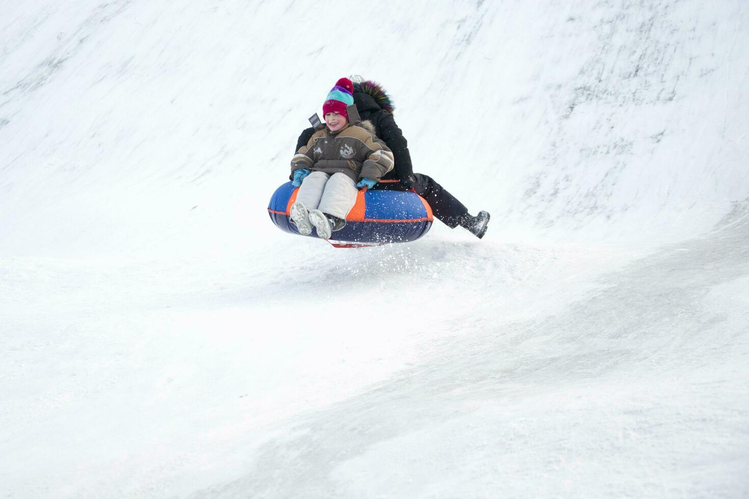 kind rodelen cheesecake.sleeën uit een sneeuw glijbaan.ski jumping Aan buizen. winter kinderen vakantie foto