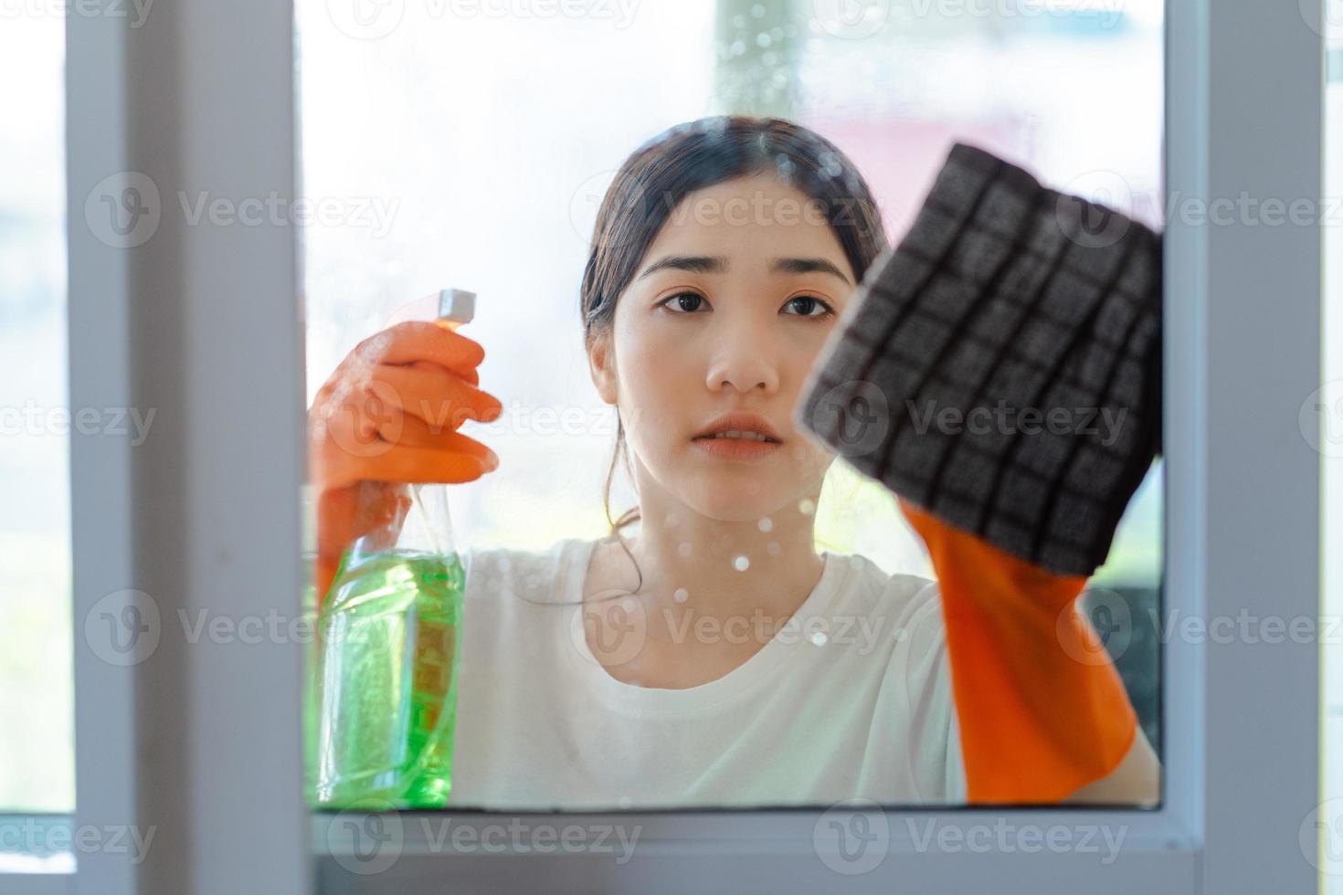 mooie aziatische vrouw die de glazen deur van de slaapkamer schoonmaakt foto