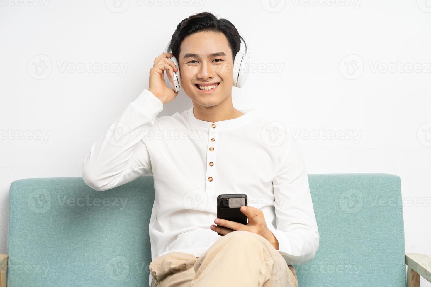 Aziatische zakenman die draadloze hoofdtelefoons draagt en video's op smartphone bekijkt foto