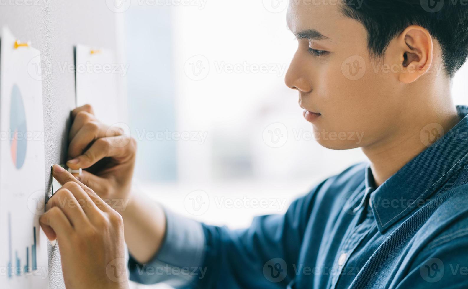 Aziatische zakenman plakte een plakbriefje op het bord om zich voor te bereiden op de presentatie foto