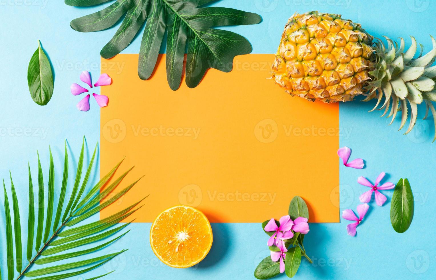 zomerachtergrond met sinaasappel, ananas, bloem en blad op blauwe achtergrond foto