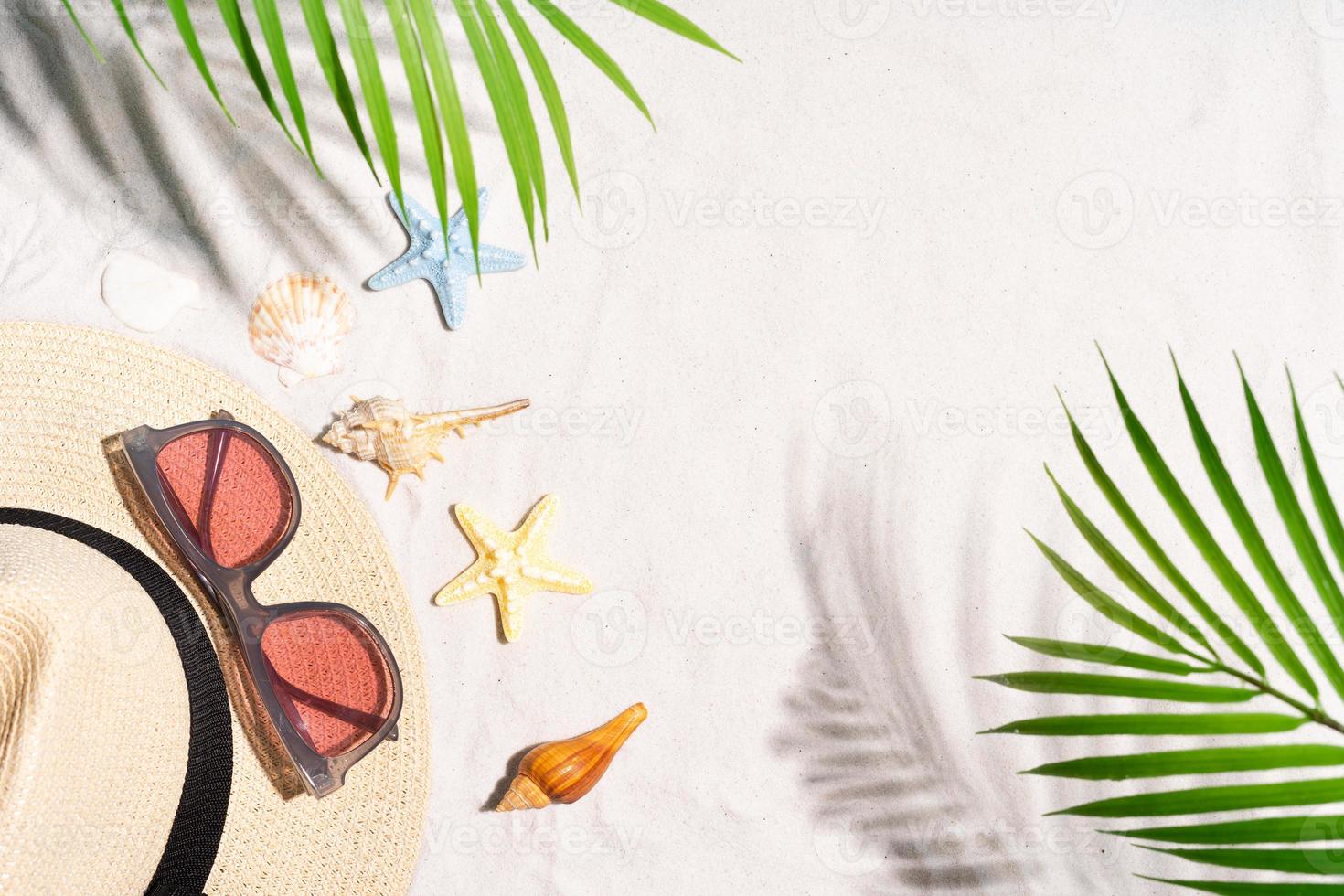 zomerachtergrond met zeeschelp, zonnebril en hoed op het zand foto