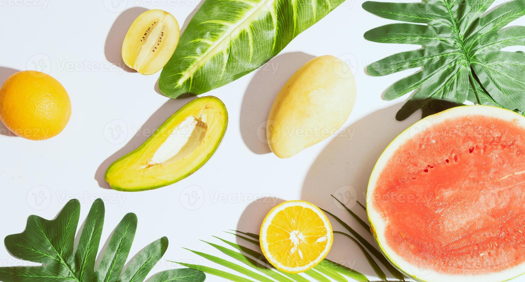 tropisch fruit zoals mango, sinaasappel, watermeloen, avocado zijn gerangschikt op een witte achtergrond foto