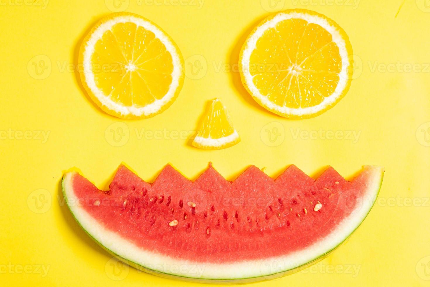 stukjes sinaasappel en stukjes watermeloen gerangschikt in de vorm van een menselijk gezicht foto
