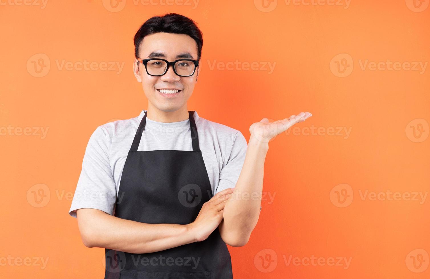 portret van Aziatische mannelijke ober die zich voordeed op een oranje achtergrond orange foto