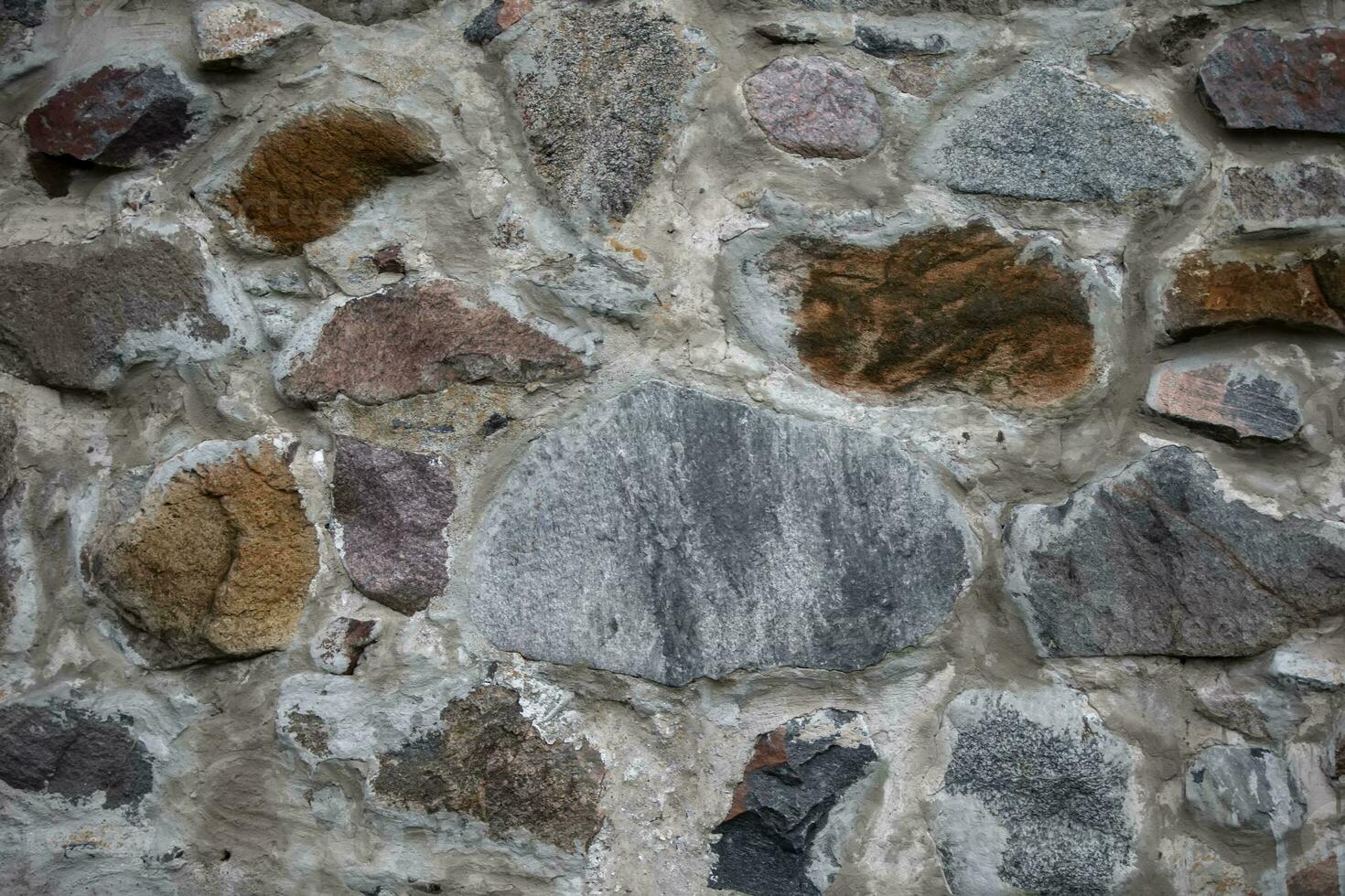 een oude steen muur bestaande van stenen van verschillend vormen en samenstelling. foto