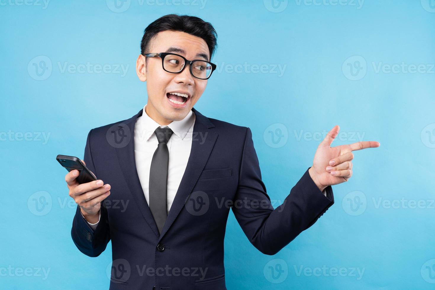 Aziatische zakenman die een pak draagt met een smartphone op een blauwe achtergrond foto