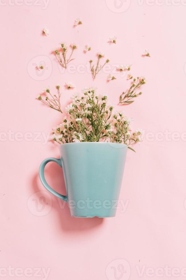 chrysanten in een blauwe kop op een roze achtergrond foto