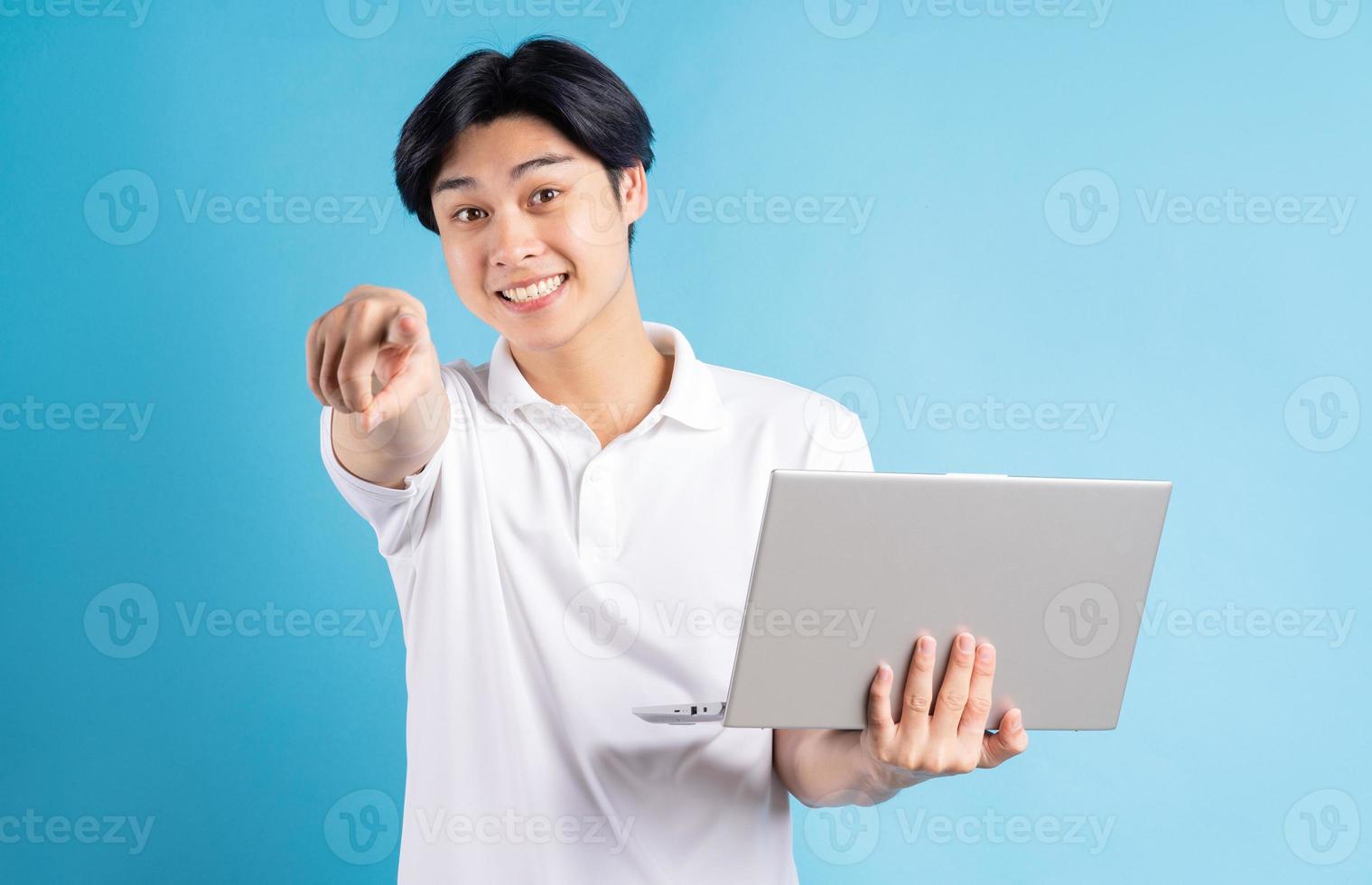 de Aziatische man hield zijn laptop vast en wees met zijn hand? foto