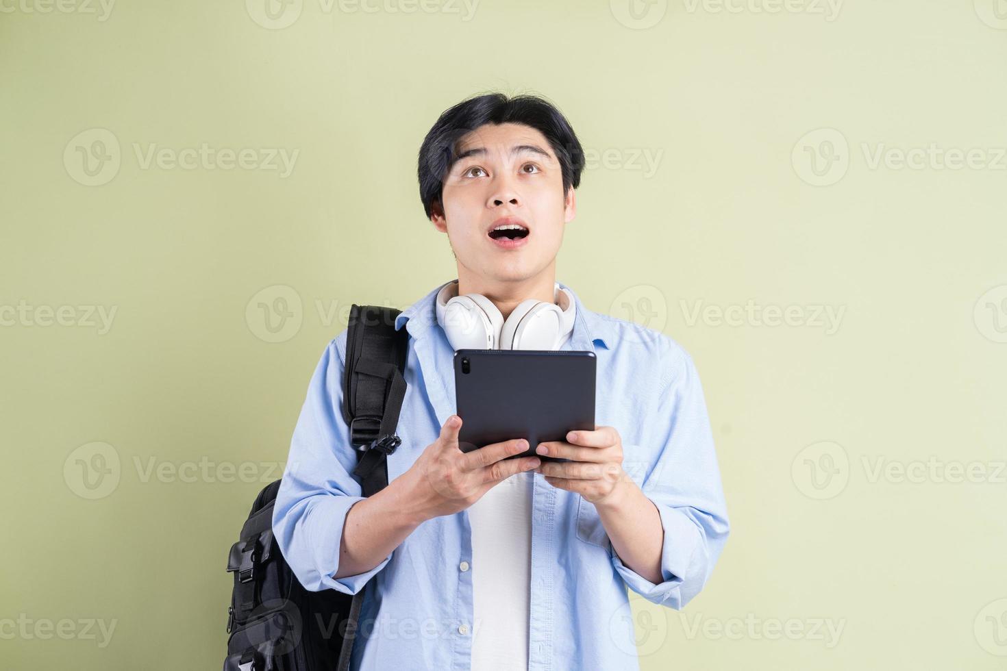 mannelijke Aziatische student die de tablet gebruikte en met een verbaasde uitdrukking opkeek foto