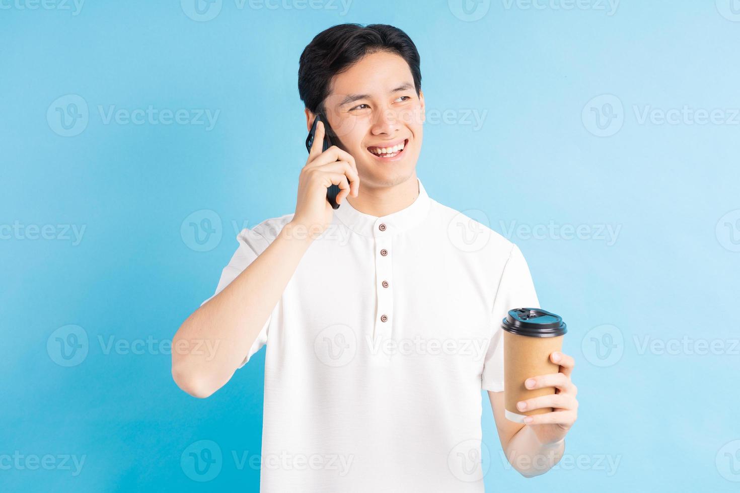 een foto van een knappe Aziatische man die belt en een kopje koffie in zijn hand houdt