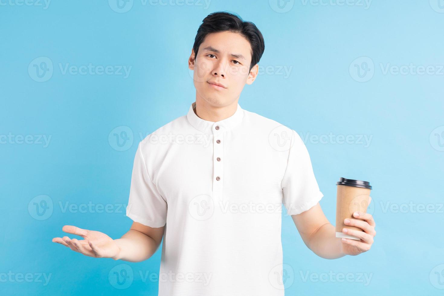 een foto van een knappe Aziatische jongen die een papieren beker in zijn hand houdt met een verbaasde uitdrukking