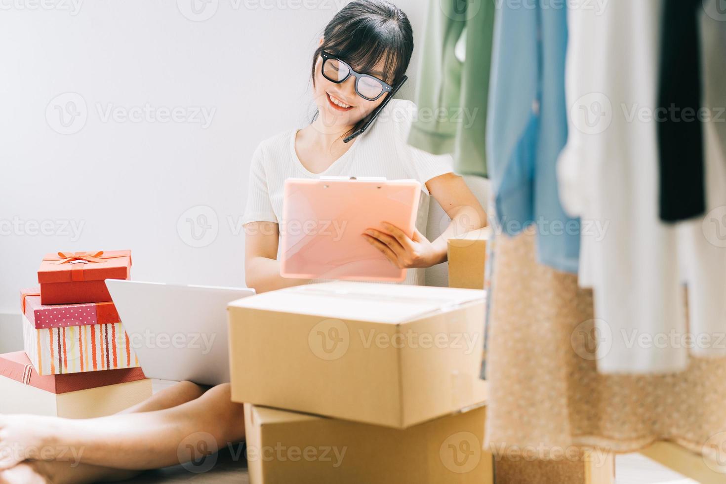 jonge Aziatische zakenvrouw zit op de grond om haar bestellingen van e-commercesites te controleren foto