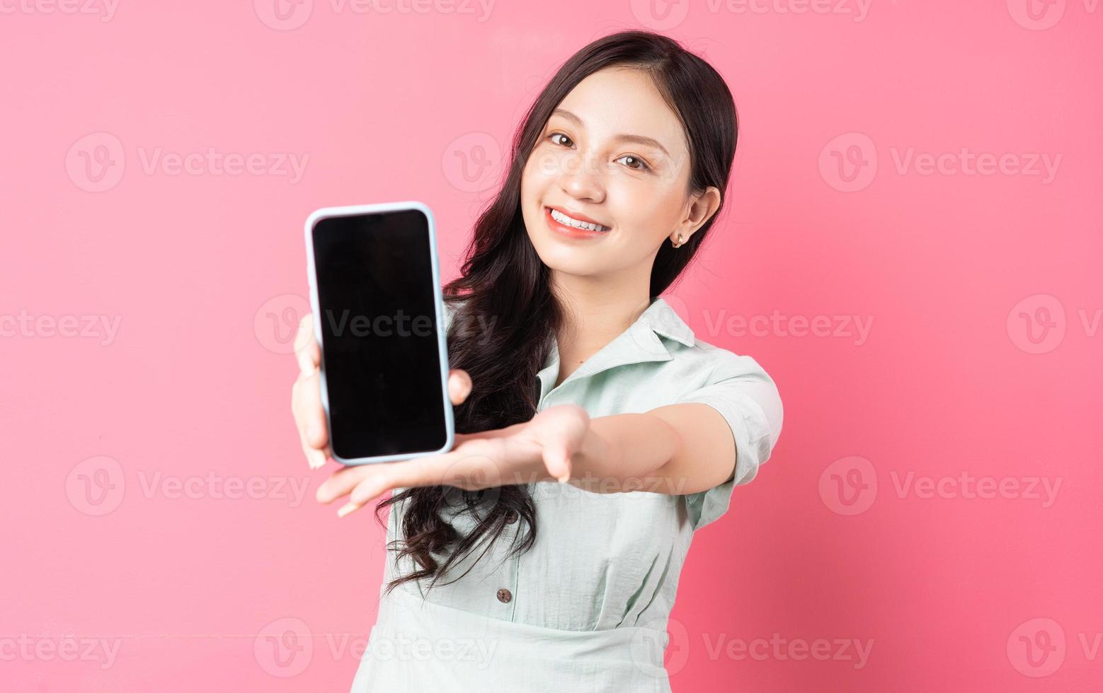 jonge aziatische vrouw die telefoon in de hand houdt en naar voren houdt foto