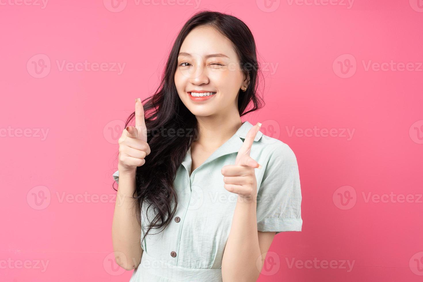 jonge aziatische vrouw wijst met opgewonden uitdrukking foto