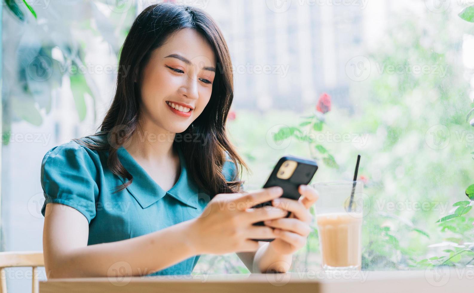 jonge aziatische vrouw die smartphone gebruikt om in café te werken? foto