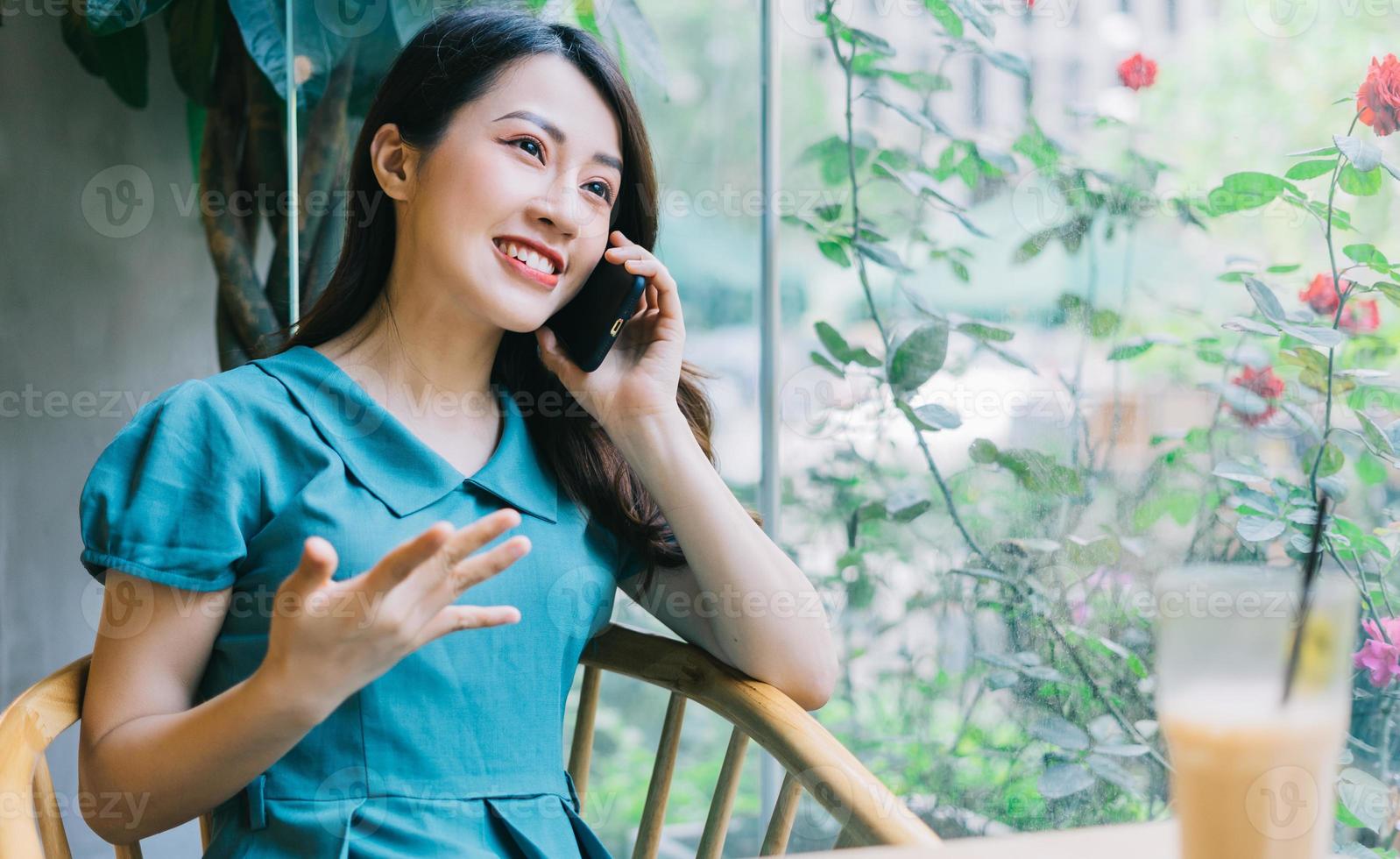 jonge aziatische vrouw die smartphone gebruikt bij coffeeshop foto