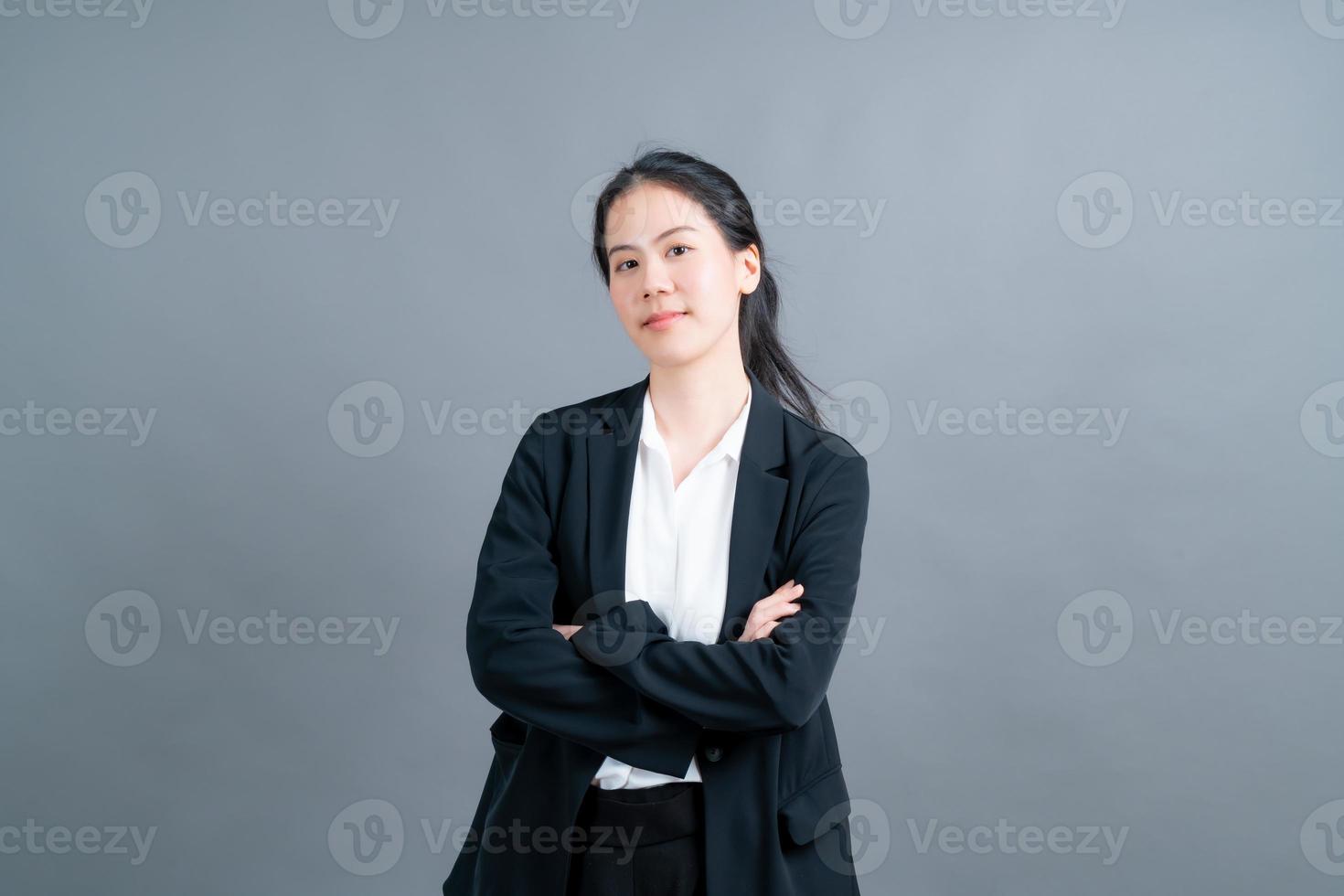 gelukkige aziatische vrouw met blij gezicht in kantoorkleren op grijze achtergrond foto