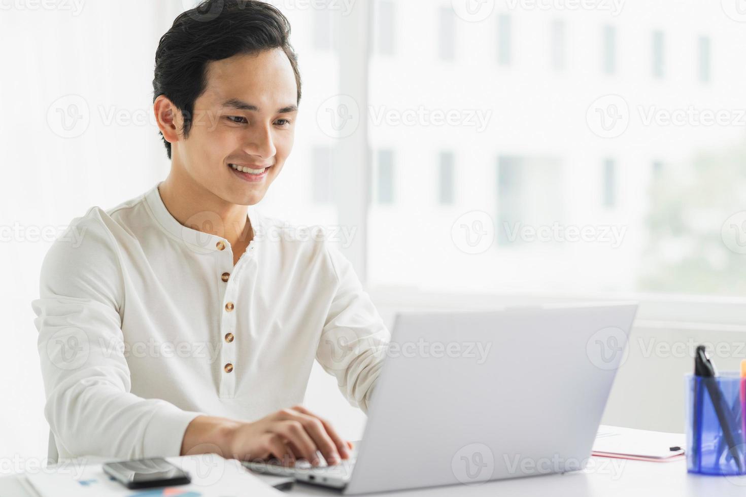 portret van mannelijke werknemer die aan computer met gelukkige uitdrukking werkt foto