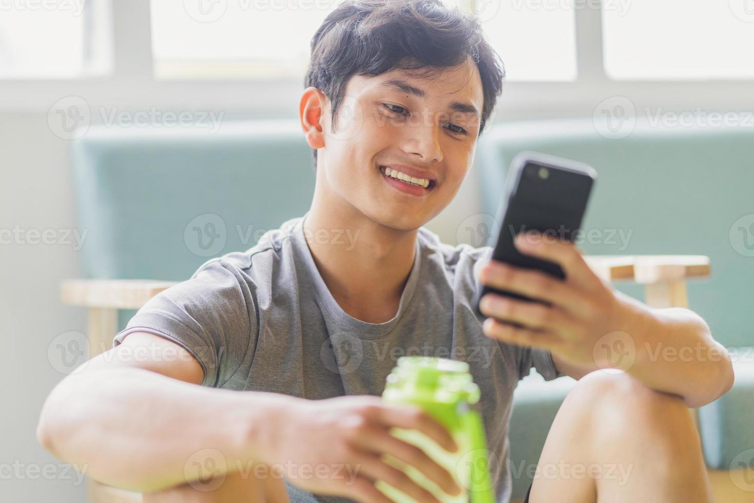 Aziatische man rust en gebruikt de telefoon na het sporten foto