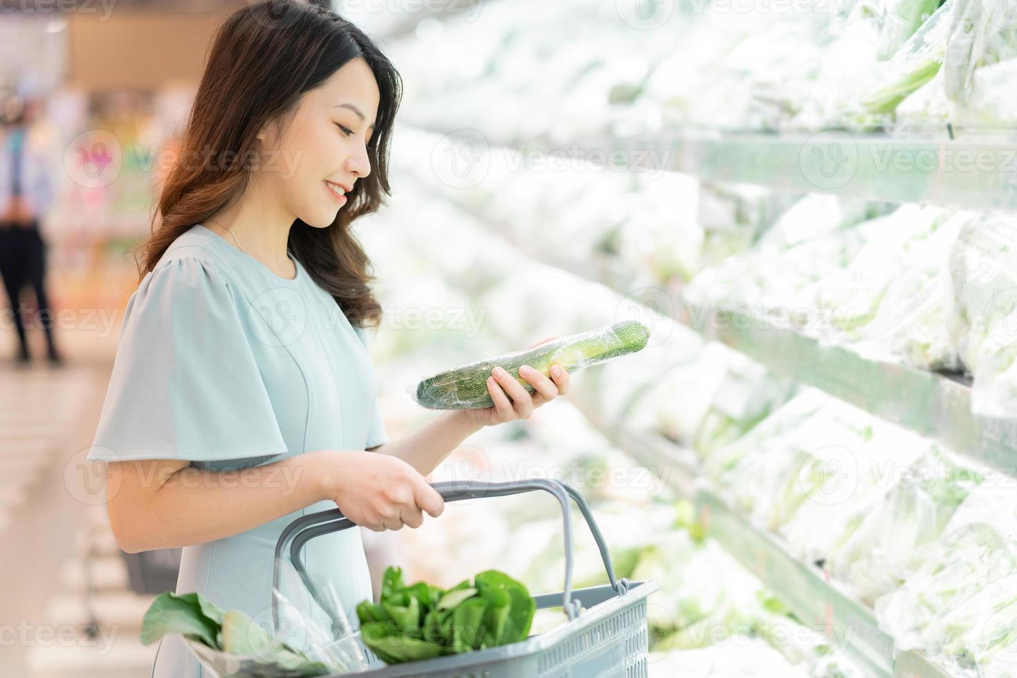 het jonge meisje kiest ervoor om groenten te kopen in de supermarkt foto