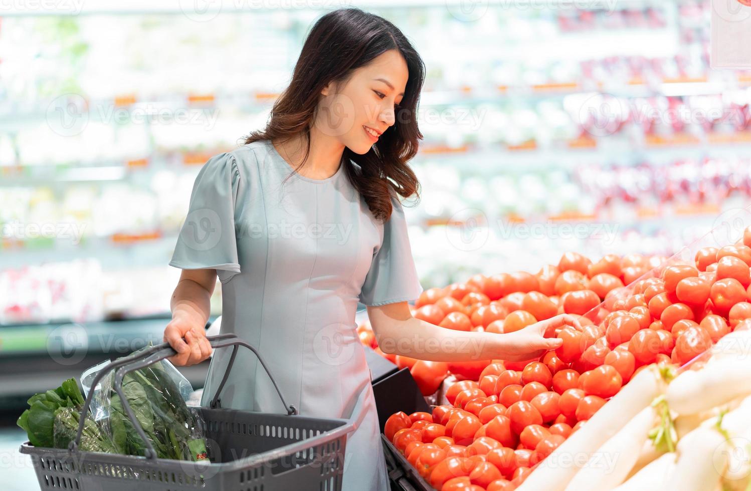 het jonge meisje kiest ervoor om groenten te kopen in de supermarkt foto