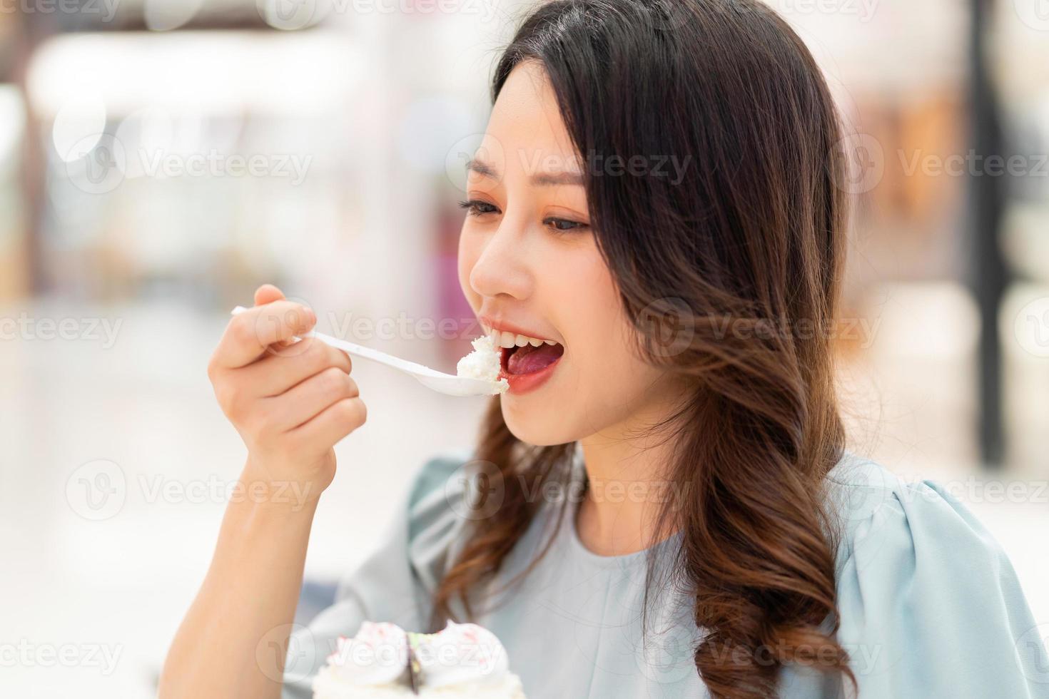 jong meisje zit alleen slagroomtaart te eten in het winkelcentrum foto