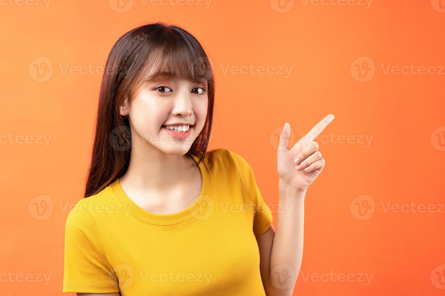 afbeelding van een jong Aziatisch meisje met een geel t-shirt op een oranje achtergrond foto