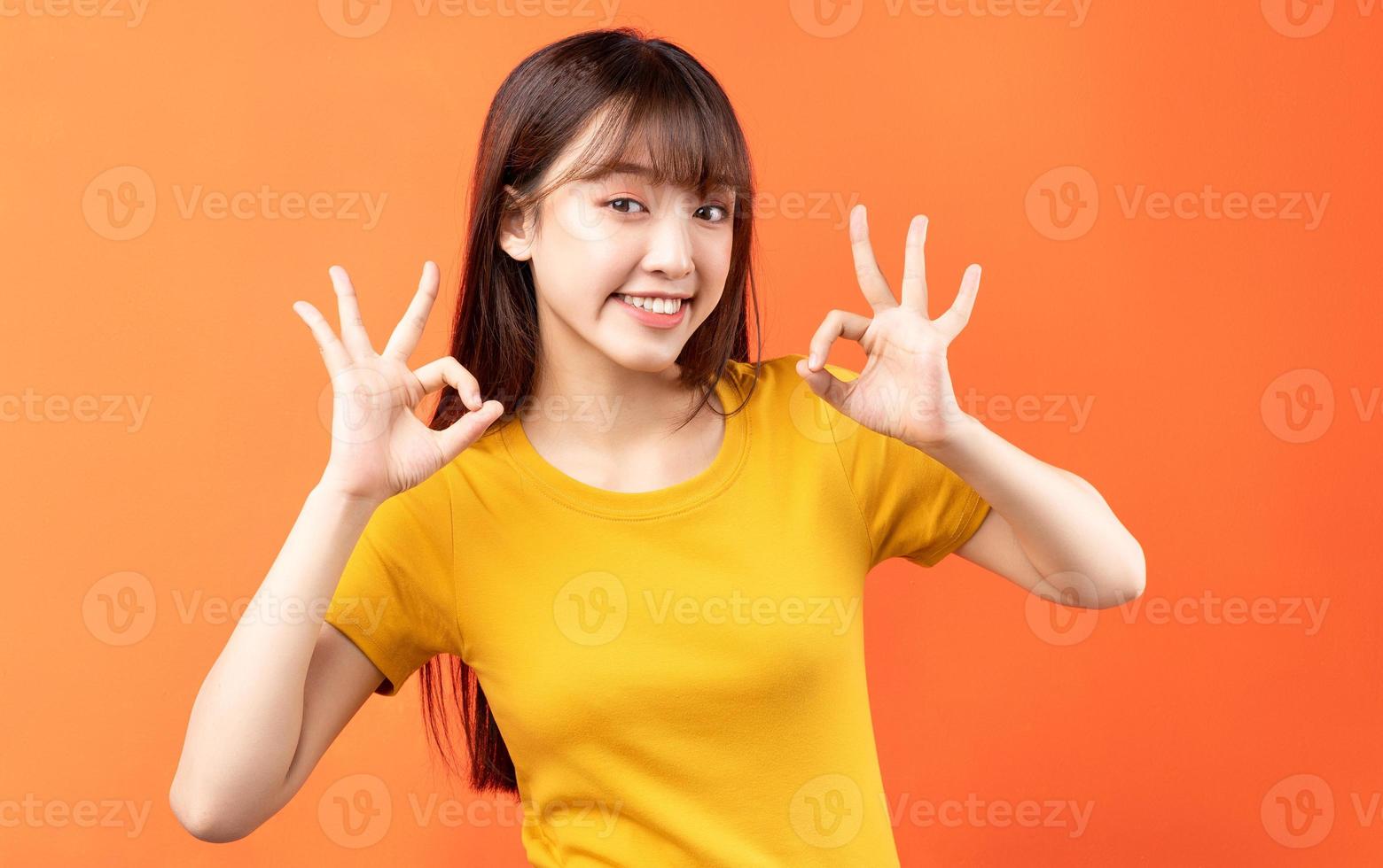 afbeelding van een jonge Aziatische vrouw die een geel t-shirt draagt op een oranje achtergrond orange foto