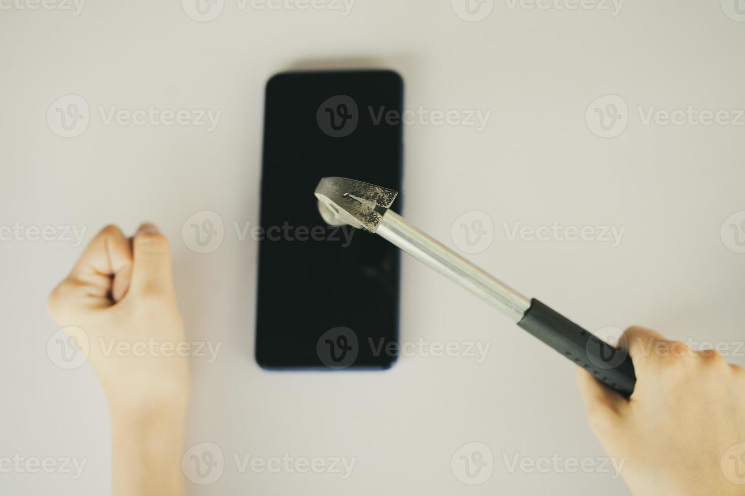 Aziatische vrouw die hamer gebruikt om haar smartphone te breken foto