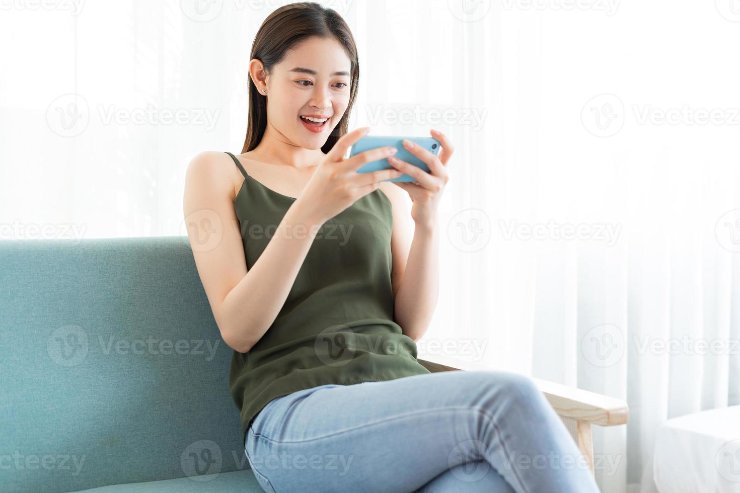 jonge aziatische vrouw die een spel speelt op de telefoon foto