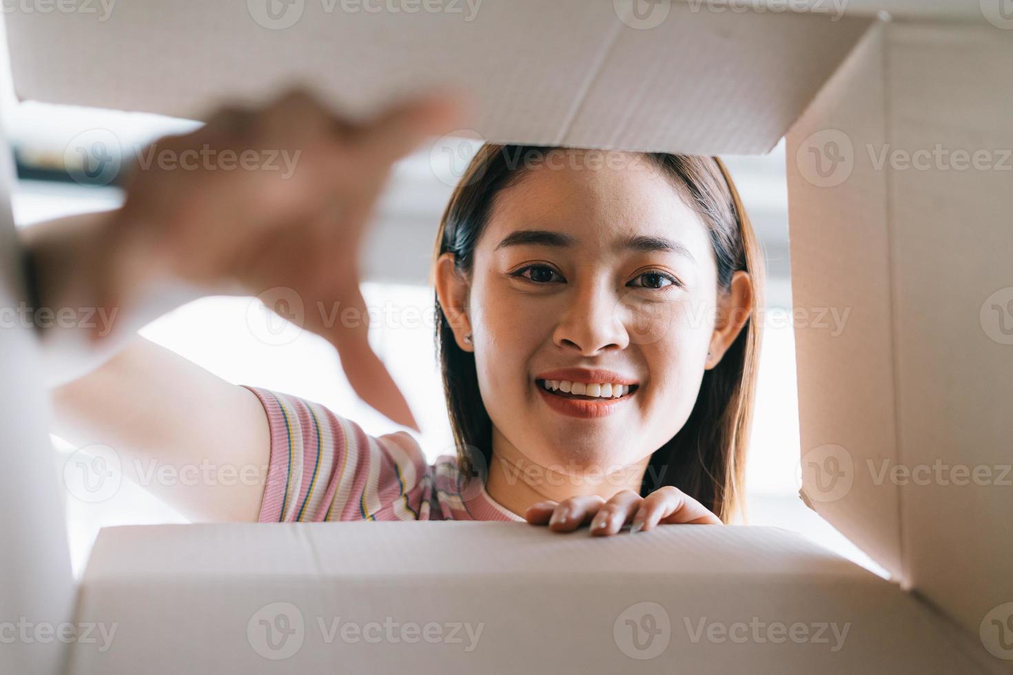 jonge aziatische vrouw opent het nieuwe pakket dat naar huis is gestuurd foto