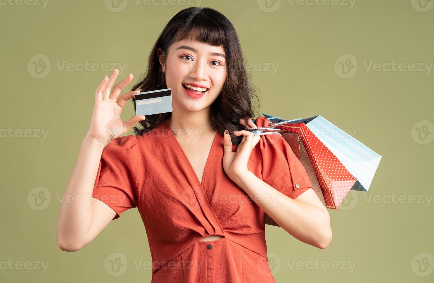 aziatische vrouw die een boodschappentas vasthoudt en een bankkaart omhoog houdt foto