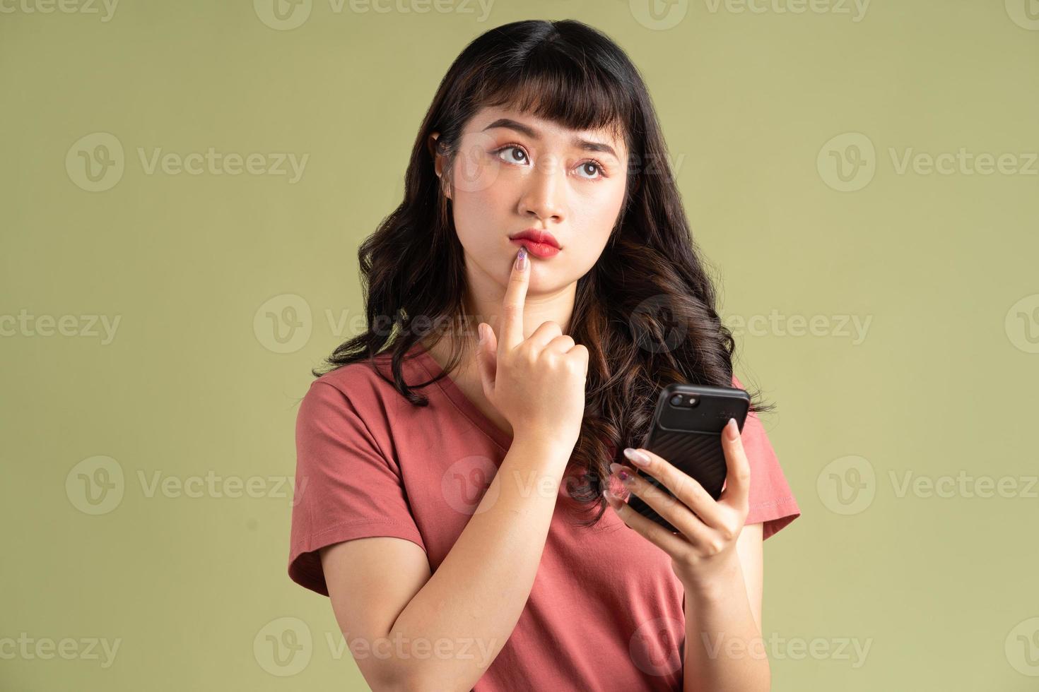 de Aziatische vrouw hield de telefoon met een bedachtzame uitdrukking vast foto